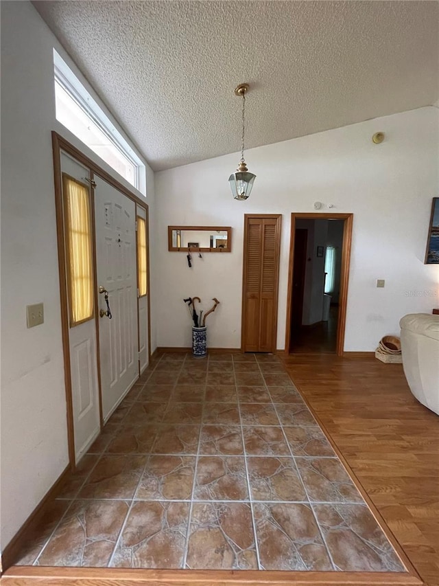 entryway with vaulted ceiling, hardwood / wood-style floors, and a textured ceiling