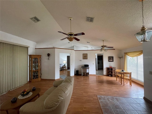 living room with hardwood / wood-style flooring, ceiling fan, lofted ceiling, and a textured ceiling