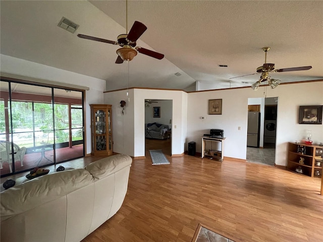 unfurnished living room with light hardwood / wood-style flooring, ceiling fan, a textured ceiling, washer / clothes dryer, and vaulted ceiling