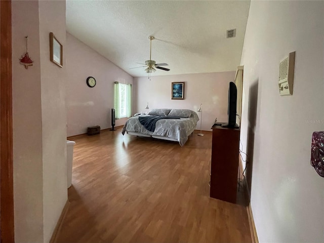 bedroom with ceiling fan, lofted ceiling, light hardwood / wood-style floors, and a textured ceiling