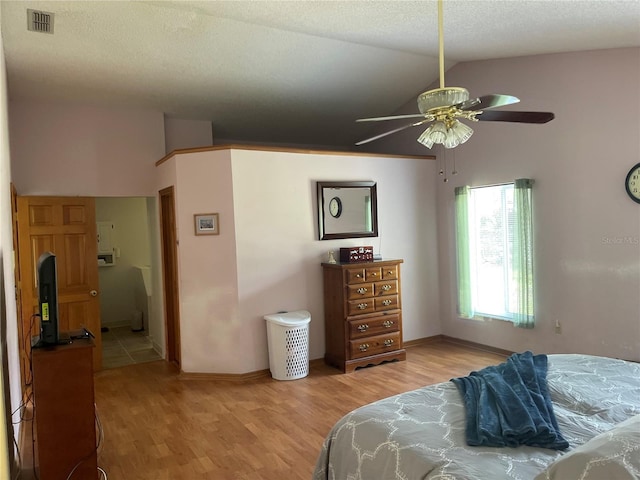 bedroom featuring vaulted ceiling, light hardwood / wood-style floors, and a textured ceiling