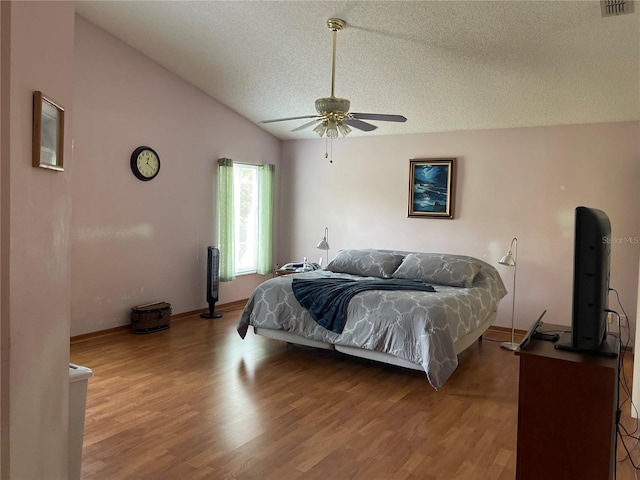 bedroom with ceiling fan, vaulted ceiling, a textured ceiling, and light wood-type flooring