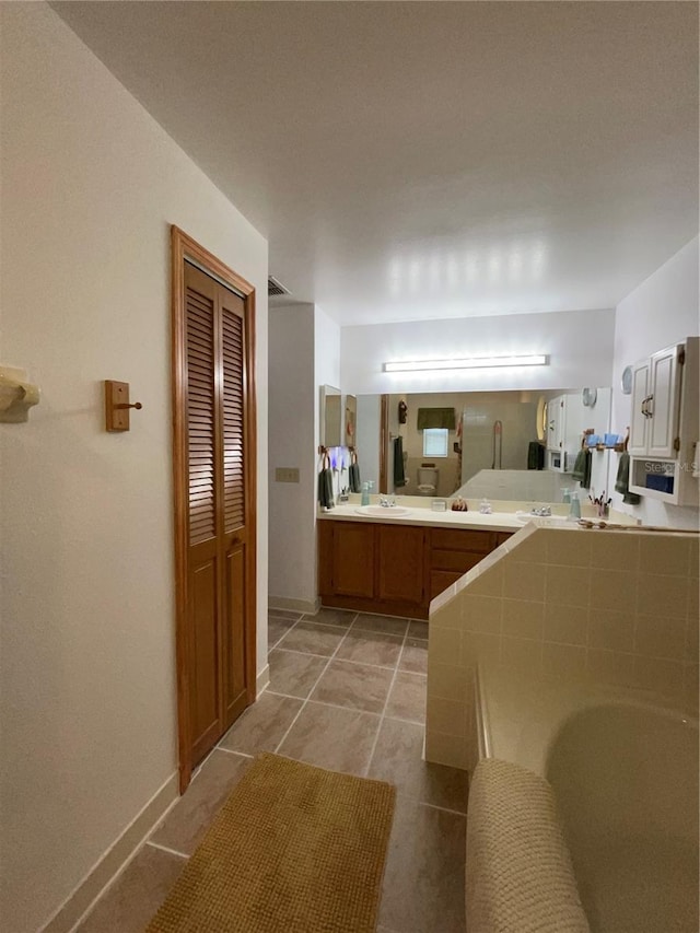 bathroom with tile patterned flooring, vanity, and a washtub