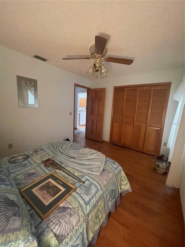 bedroom with hardwood / wood-style flooring, ceiling fan, a textured ceiling, and a closet