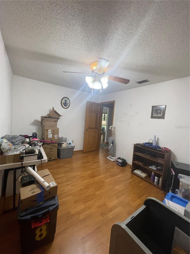 interior space featuring hardwood / wood-style flooring, ceiling fan, and a textured ceiling