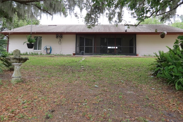 rear view of house featuring a yard and a sunroom