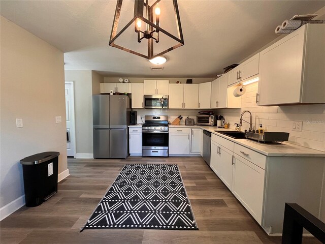 kitchen with hanging light fixtures, appliances with stainless steel finishes, sink, and white cabinets