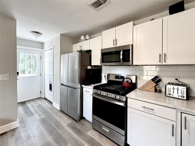 kitchen with white cabinetry, tasteful backsplash, stainless steel appliances, and light hardwood / wood-style floors