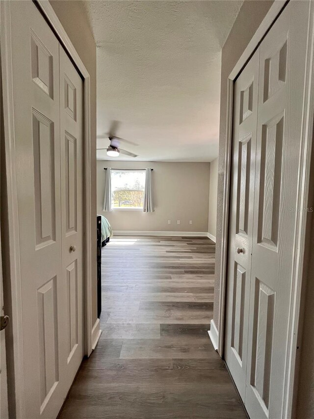 corridor featuring wood-type flooring and a textured ceiling