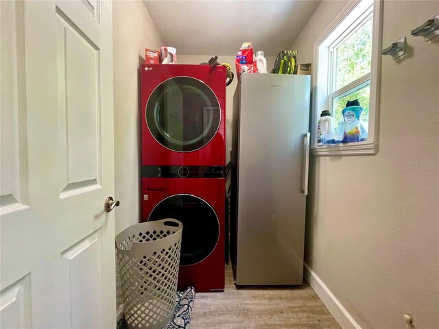 laundry room featuring stacked washer / dryer and light hardwood / wood-style flooring