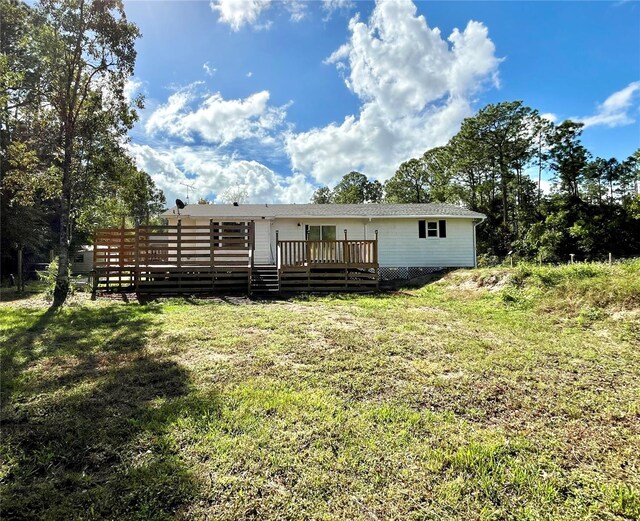 rear view of property featuring a deck and a lawn