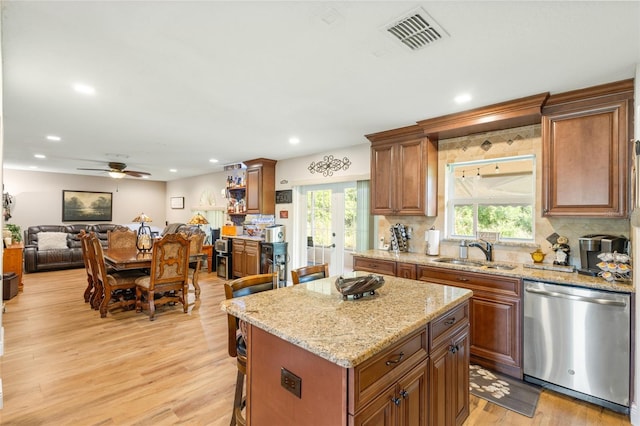 kitchen with stainless steel dishwasher, sink, a wealth of natural light, and a kitchen bar