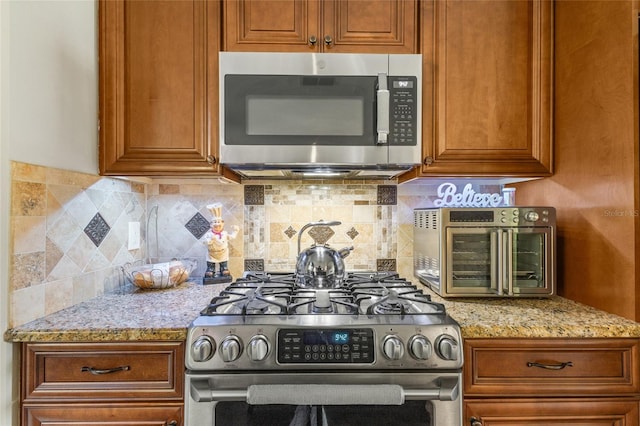 kitchen with appliances with stainless steel finishes, light stone countertops, and tasteful backsplash