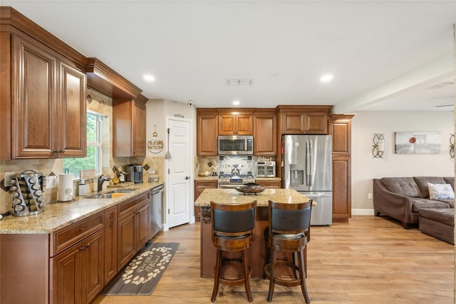 kitchen with tasteful backsplash, stainless steel appliances, light hardwood / wood-style flooring, sink, and a kitchen breakfast bar