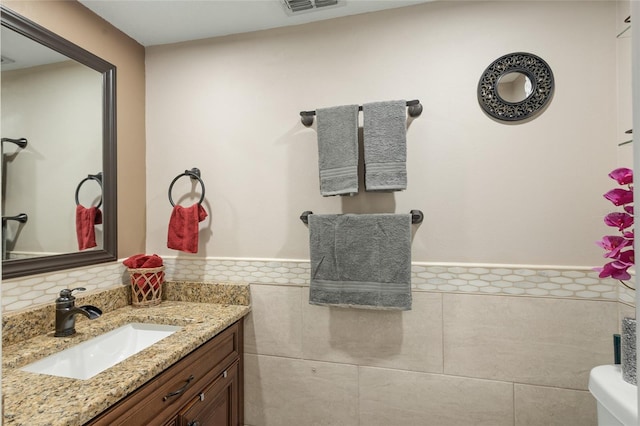 bathroom featuring tile walls, backsplash, toilet, and vanity