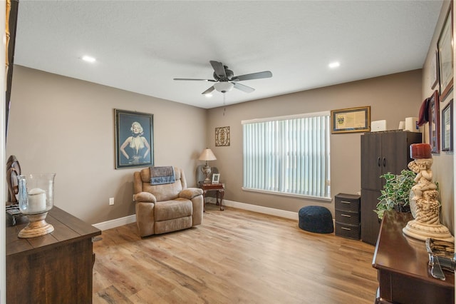 sitting room with ceiling fan and light wood-type flooring