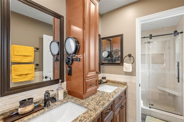 bathroom featuring double sink vanity, a shower with door, and tasteful backsplash