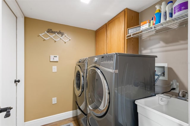 laundry room featuring light hardwood / wood-style flooring, sink, washing machine and dryer, and cabinets