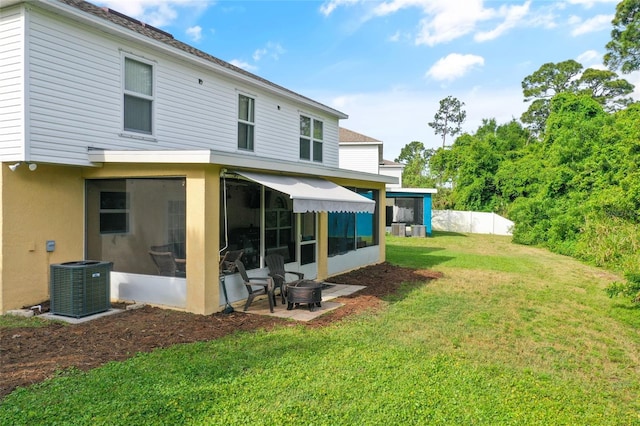 rear view of property featuring central AC unit, a patio area, and a lawn