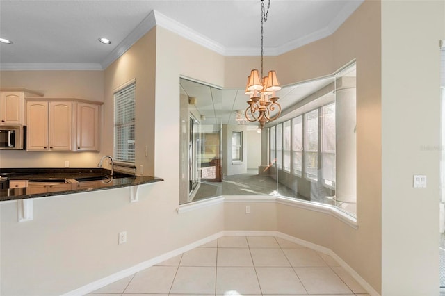 kitchen featuring an inviting chandelier, dark stone countertops, crown molding, decorative light fixtures, and light tile patterned floors