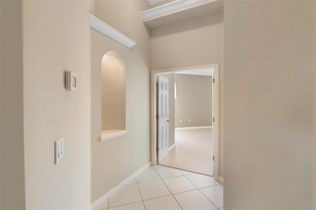 hallway featuring light tile patterned flooring and a towering ceiling