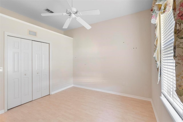 unfurnished bedroom with ceiling fan, light wood-type flooring, multiple windows, and a closet