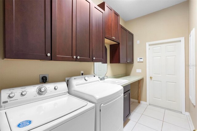 washroom with light tile patterned flooring, cabinets, sink, and washing machine and clothes dryer