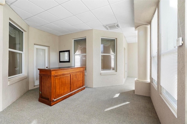 hall featuring a paneled ceiling and a wealth of natural light