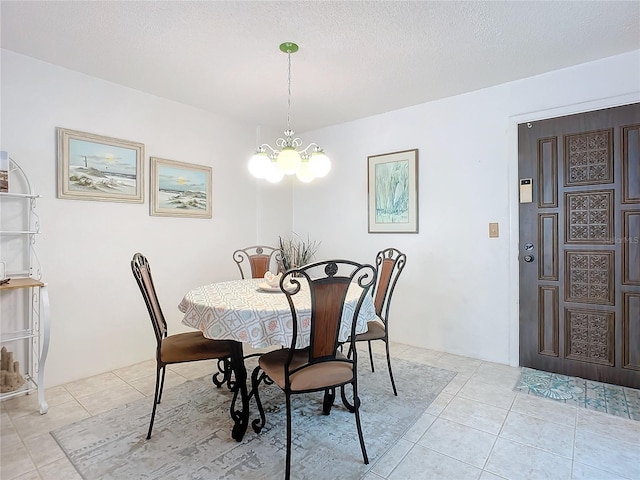 dining room featuring light tile flooring, a chandelier, and a textured ceiling