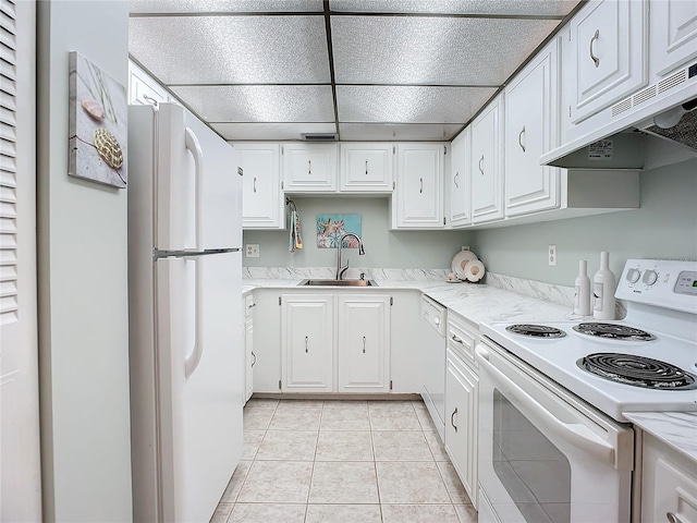 kitchen with light stone counters, light tile floors, sink, white appliances, and white cabinetry