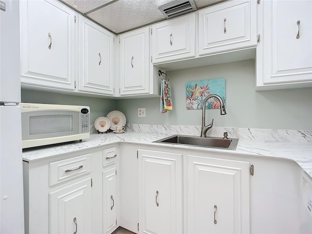 kitchen featuring white cabinetry, a textured ceiling, white appliances, and sink