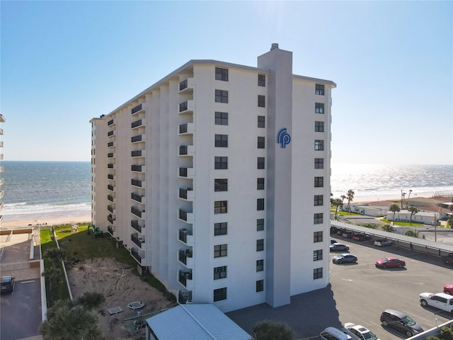 view of building exterior with a beach view and a water view