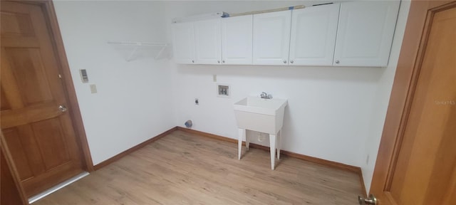 clothes washing area with washer hookup, light hardwood / wood-style flooring, and cabinets