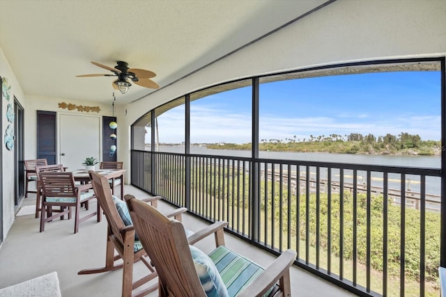 sunroom / solarium featuring ceiling fan and a water view