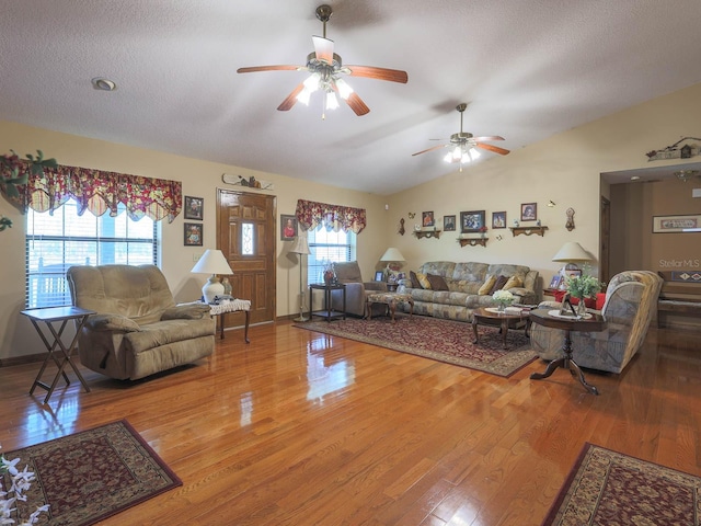 living room featuring wood-type flooring, ceiling fan, lofted ceiling, and a textured ceiling