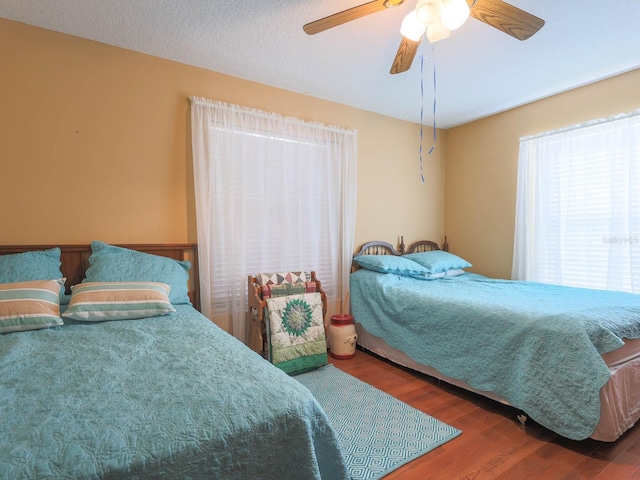 bedroom with a textured ceiling, ceiling fan, and dark wood-type flooring