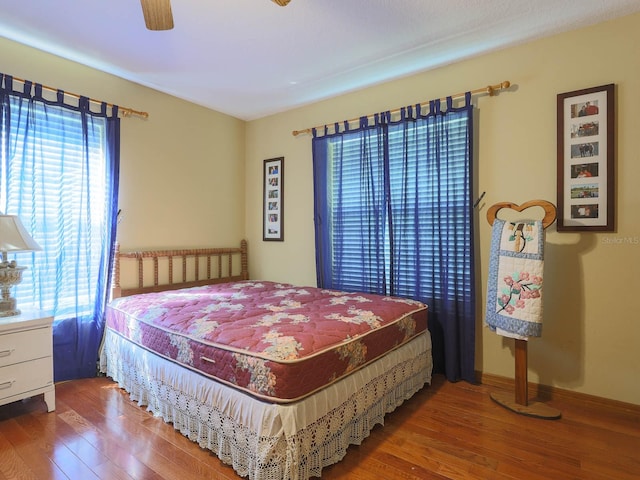 bedroom with ceiling fan, hardwood / wood-style floors, and multiple windows