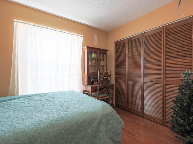 bedroom with a textured ceiling, a closet, and dark wood-type flooring