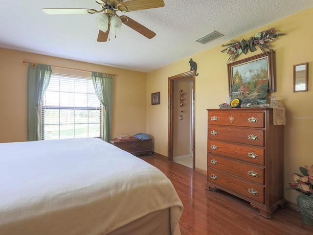 bedroom featuring ceiling fan, dark hardwood / wood-style floors, and a textured ceiling