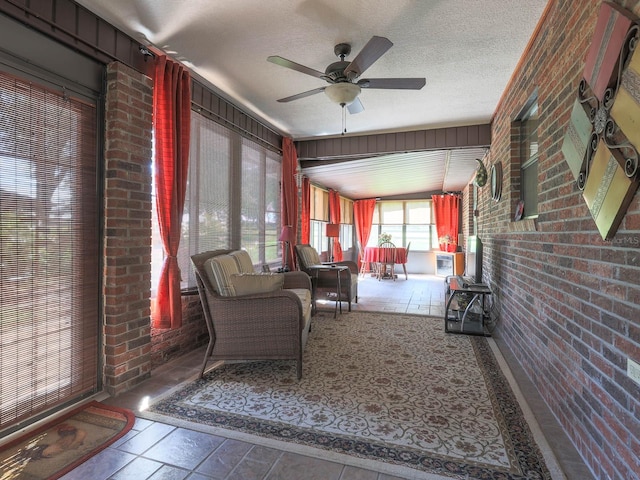 interior space with brick wall, ceiling fan, tile floors, and a textured ceiling