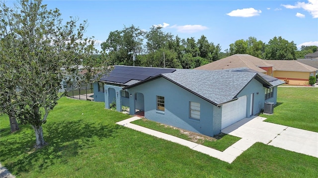 view of front of home featuring a garage, cooling unit, a front lawn, and solar panels