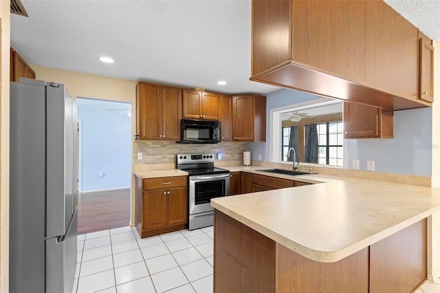 kitchen with stainless steel appliances, kitchen peninsula, sink, tasteful backsplash, and light tile patterned flooring