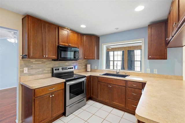 kitchen featuring stainless steel range with electric cooktop, light tile patterned floors, decorative backsplash, sink, and kitchen peninsula