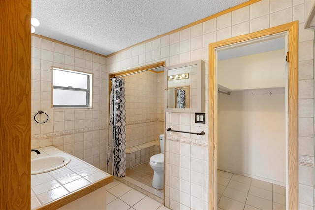 bathroom with tile walls, toilet, a textured ceiling, and tile patterned floors