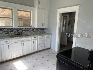 kitchen featuring backsplash, light stone counters, and white cabinetry