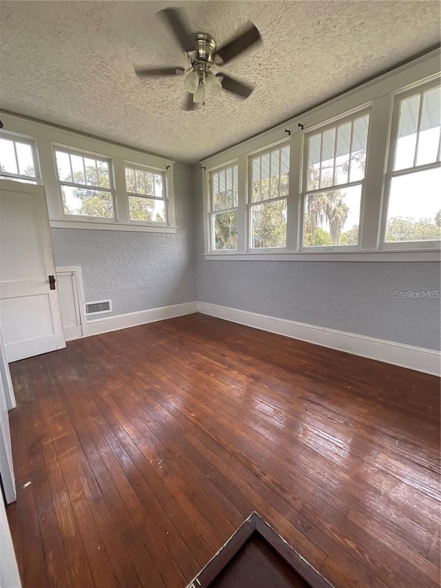 spare room with dark hardwood / wood-style floors, ceiling fan, and a textured ceiling