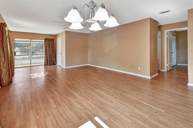 unfurnished room featuring a chandelier and light wood-type flooring