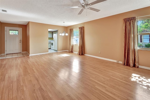 unfurnished living room with light hardwood / wood-style floors, a textured ceiling, and plenty of natural light