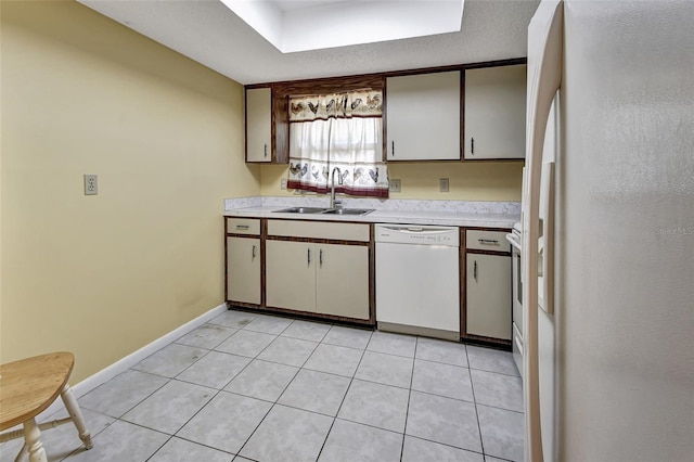 kitchen featuring sink, white cabinets, white appliances, and light tile floors