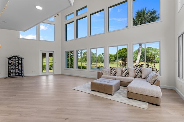 living room featuring french doors, light hardwood / wood-style floors, and a high ceiling